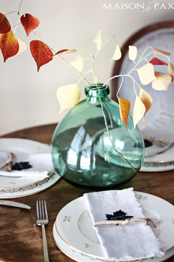 Lovely, simple Thanksgiving tablescape: a grand table and a side table with fall foliage centerpieces, simple neutral china settings, and a few pumpkins | maisondepax.com