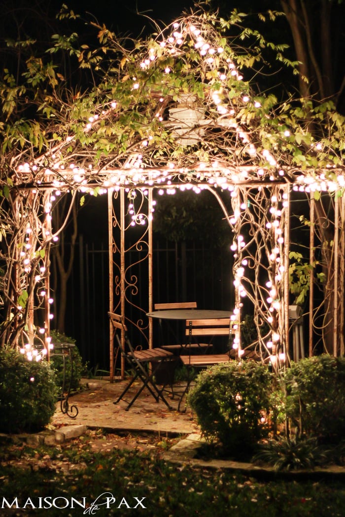 arbor with Christmas lights and a bistro table and chairs