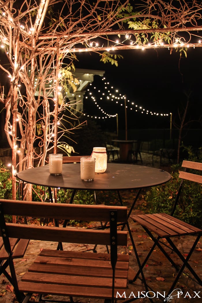 perfectly charming hot chocolate table under an arbor with christmas lights