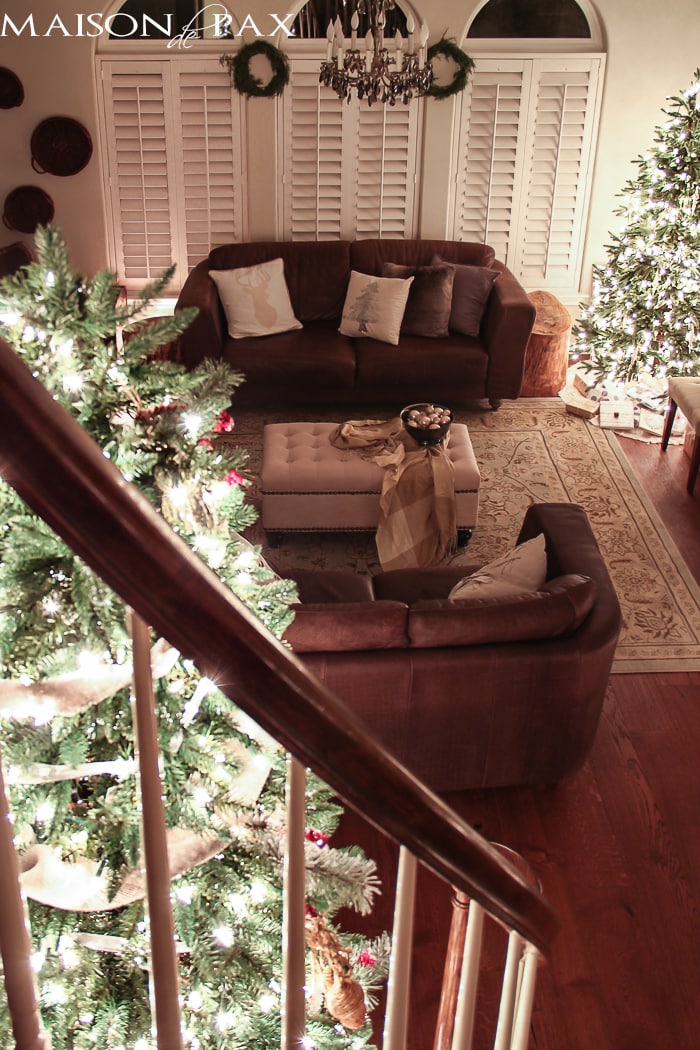 large Christmas tree in stair curve and smaller tree in living room