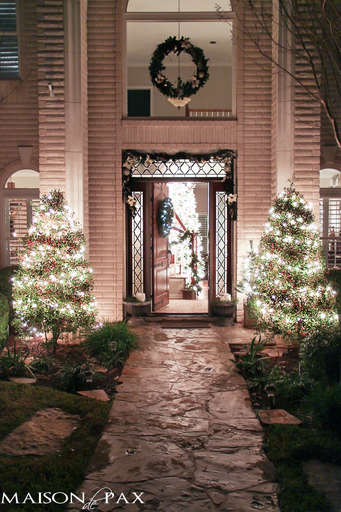 holiday front porch with garland, wreath, and lights