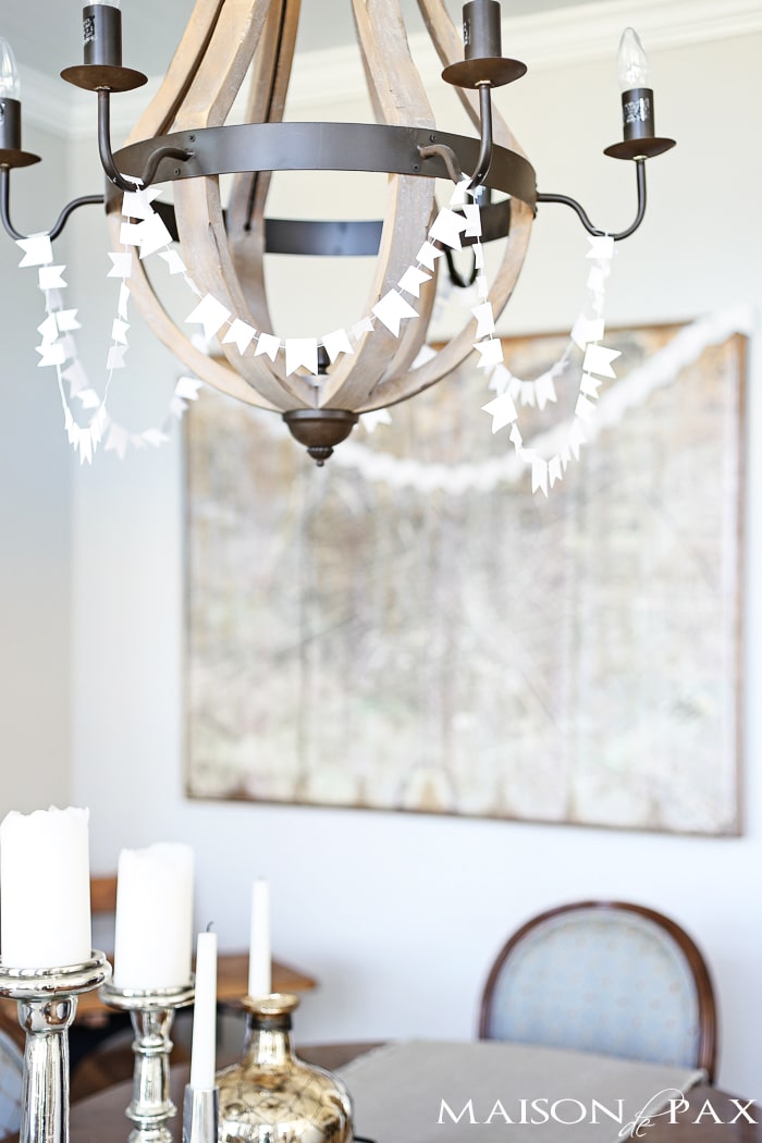sewn white paper flags draped around a wine barrel chandelier for a festive look