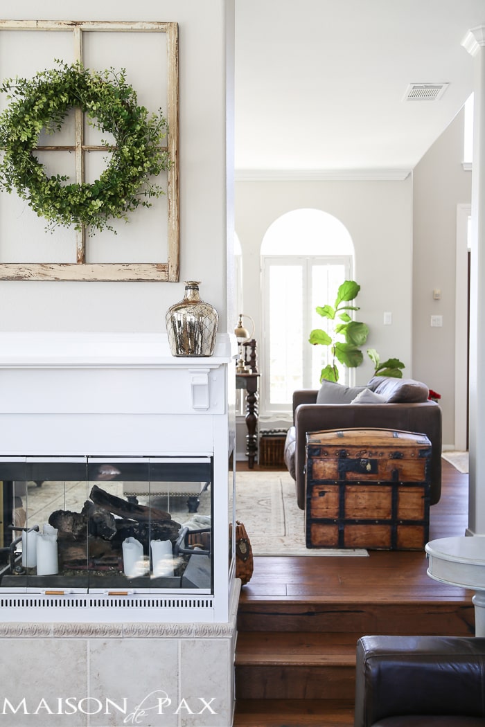 Love the wreath over the antique window above the mantel... What a beautiful home with light touches of greenery perfect for spring or summer | maisondepax.com