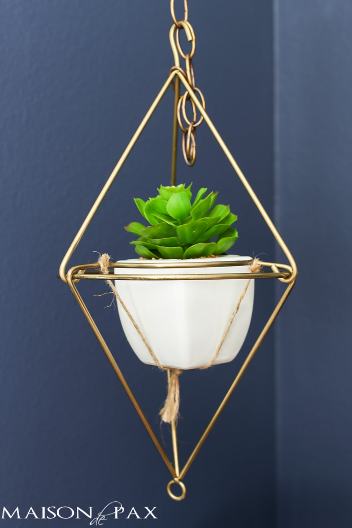 very cool modern, angular hanging plant holder in brass with a white pot and succulent