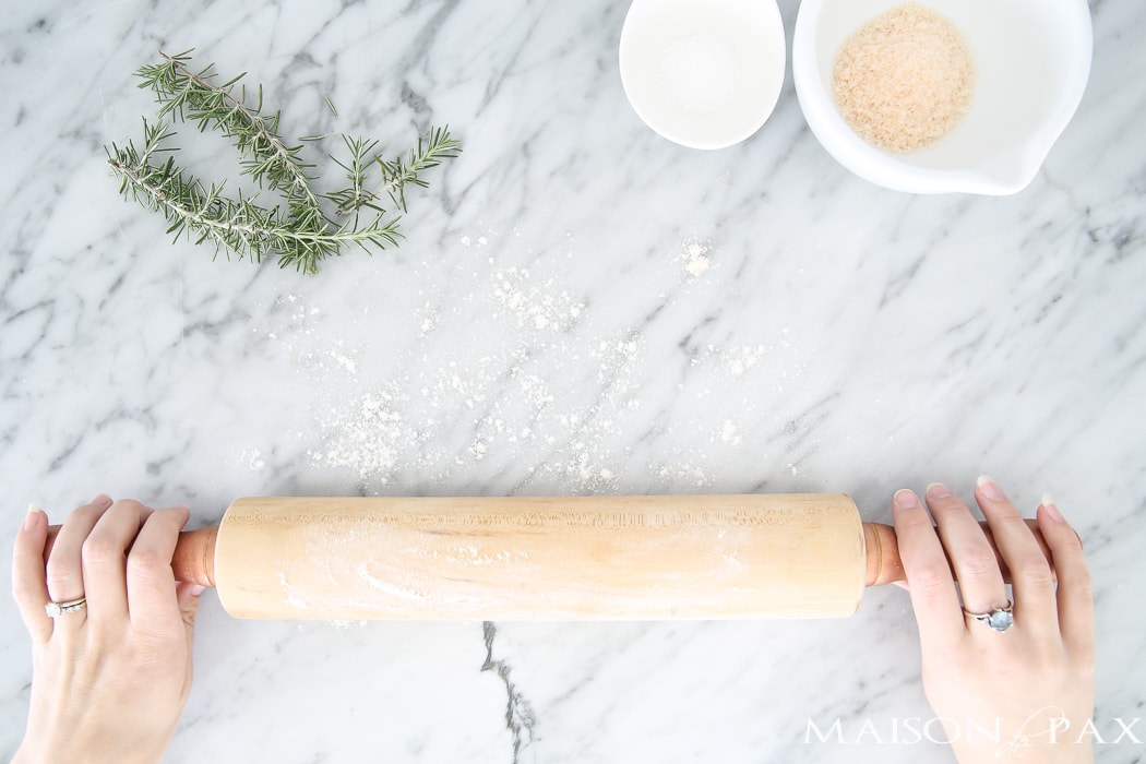 flat lay of marble countertop and rolling pin with a few sprigs of herbs- Maison de Pax