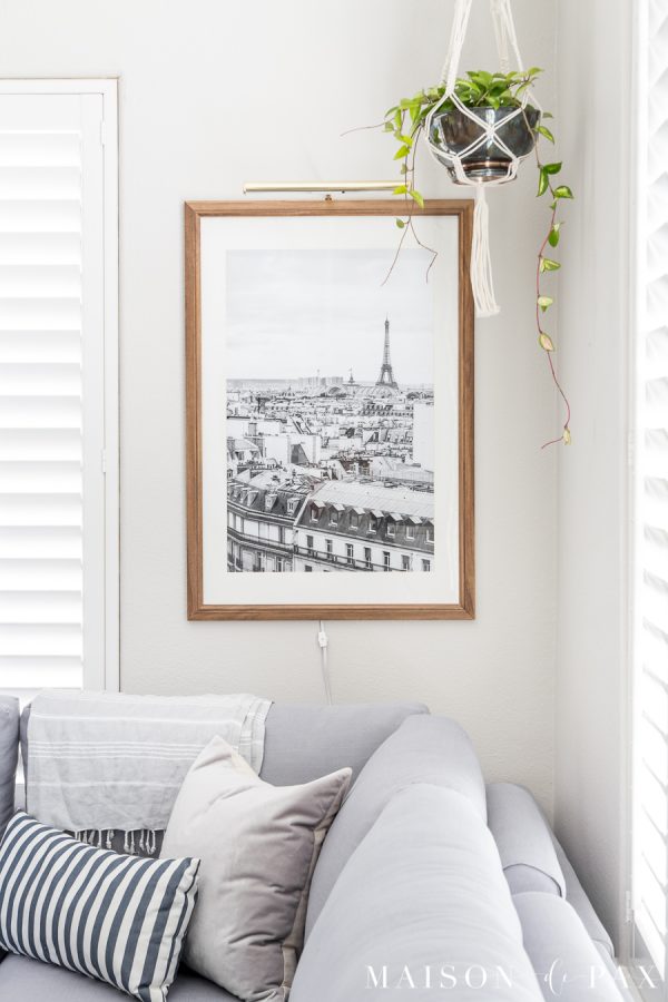 Find out the secret to inexpensive large wall art! This black and white photo is beautiful in a natural wood frame with a brass picture light above. #simplewallart #wallart #livingroomdecor