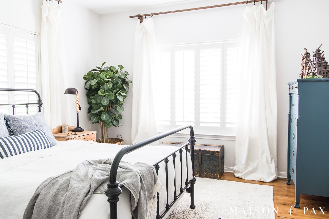 master bedroom with iron bed, white bedding, and blue accents- Maison de Pax