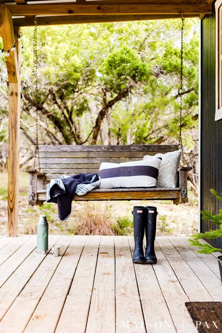 porch swing with black and white throw pillows and blanket