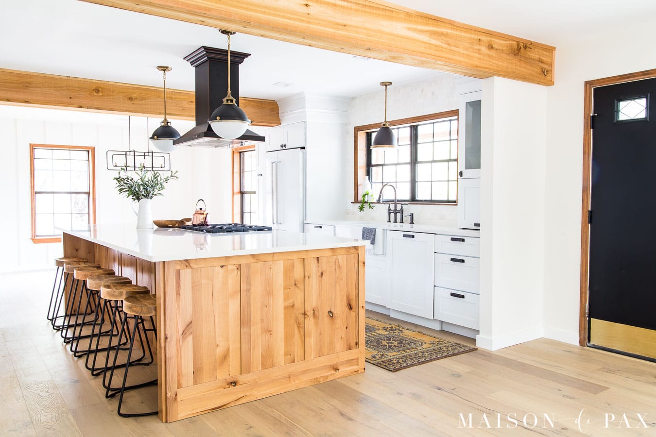big wood island in white kitchen with black hood and door | Maison de Pax