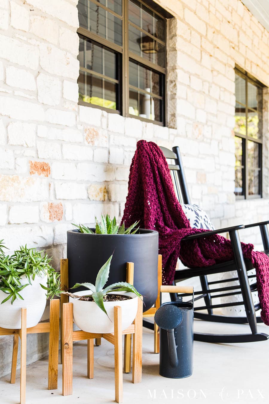 black rocking chair with black and white pots on front porch | Maison de Pax
