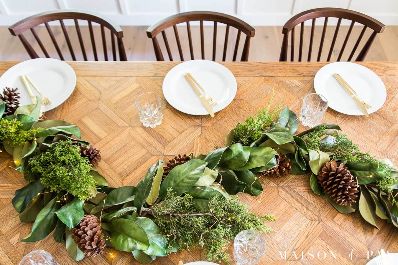 magnolia leaf garland and cedar with twinkle lights on dining table | Maison de Pax