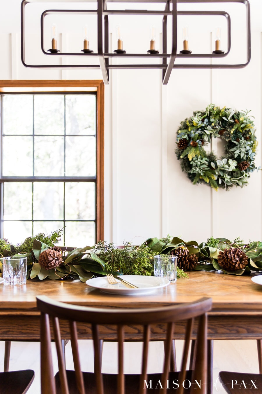 wood table with greenery centerpiece and wreath on white walls | Maison de Pax