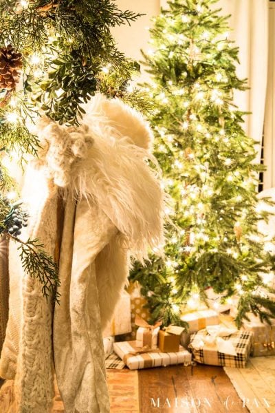 white fur stockings and greenery by tree with lights | Maison de Pax