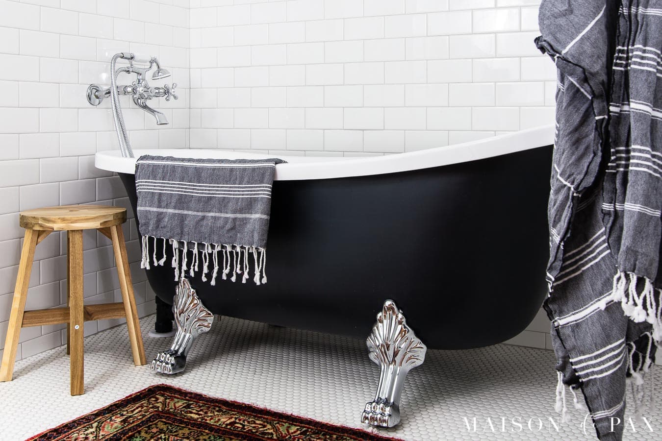 black clawfoot tub with chrome feet draped with a striped turkish towel | Maison de Pax