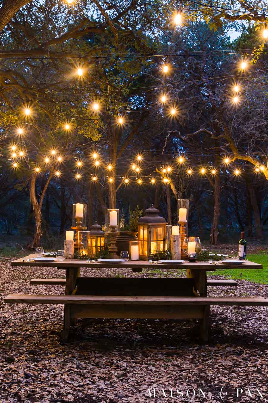 picnic table decorated with candles and string lights | Maison de Pax
