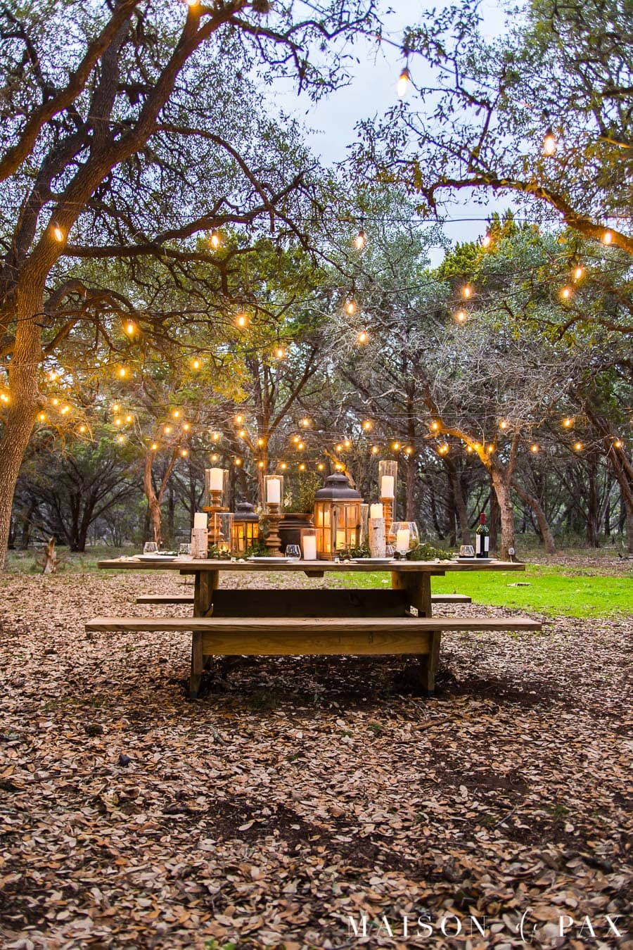 picnic table with beautiful centerpiece and string lights