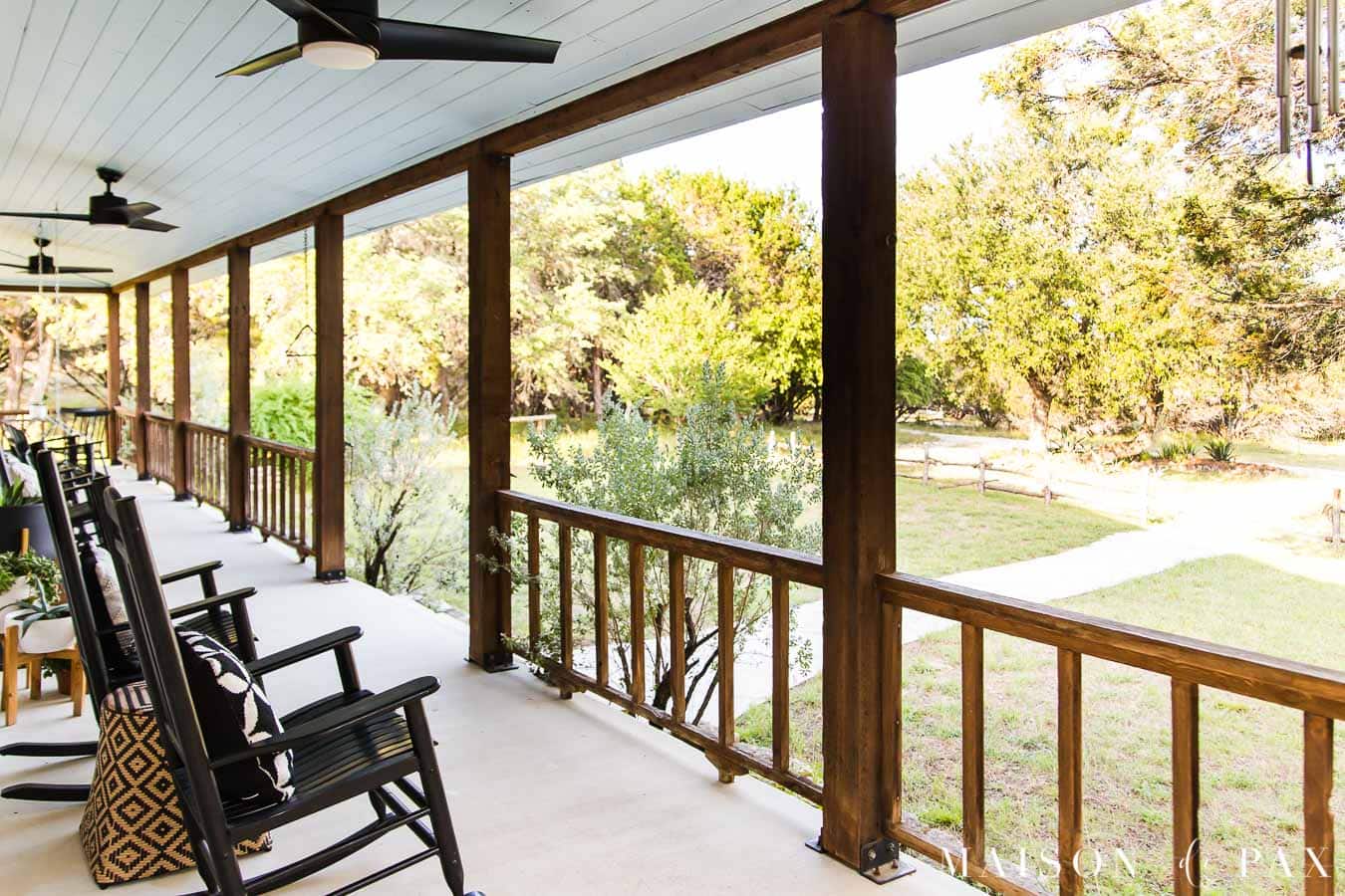 rocking chairs and a cedar porch railing overlook a texas hill country ranch | Maison de Pax
