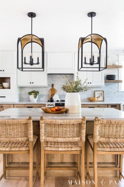 white and wood kitchen with black and gold lanterns over kitchen island