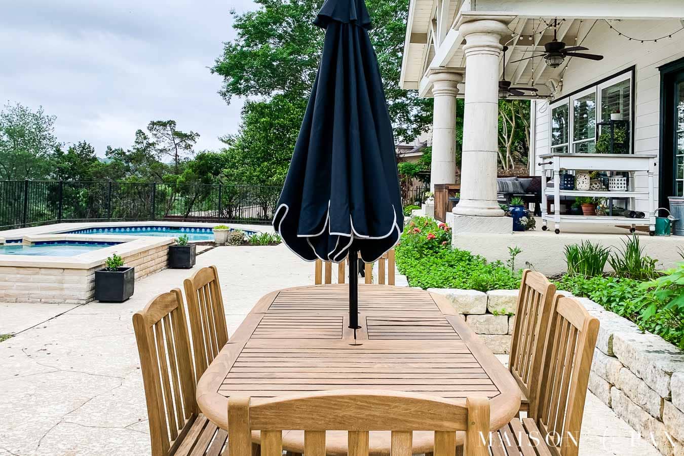 teak outdoor dining set with black umbrella
