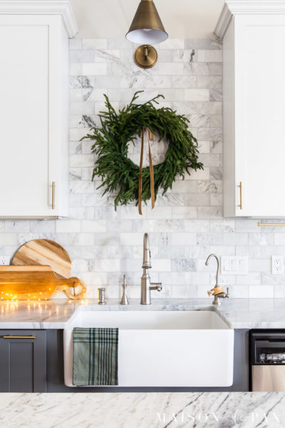 pine wreath with velvet ribbon on tile wall above farmhouse sink