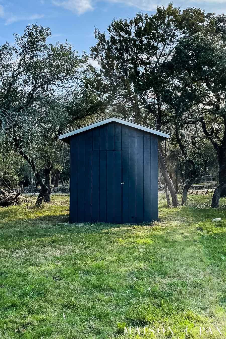 black garden shed with white trim