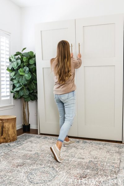 woman opening murphy bed cabinet that looks like an armoire