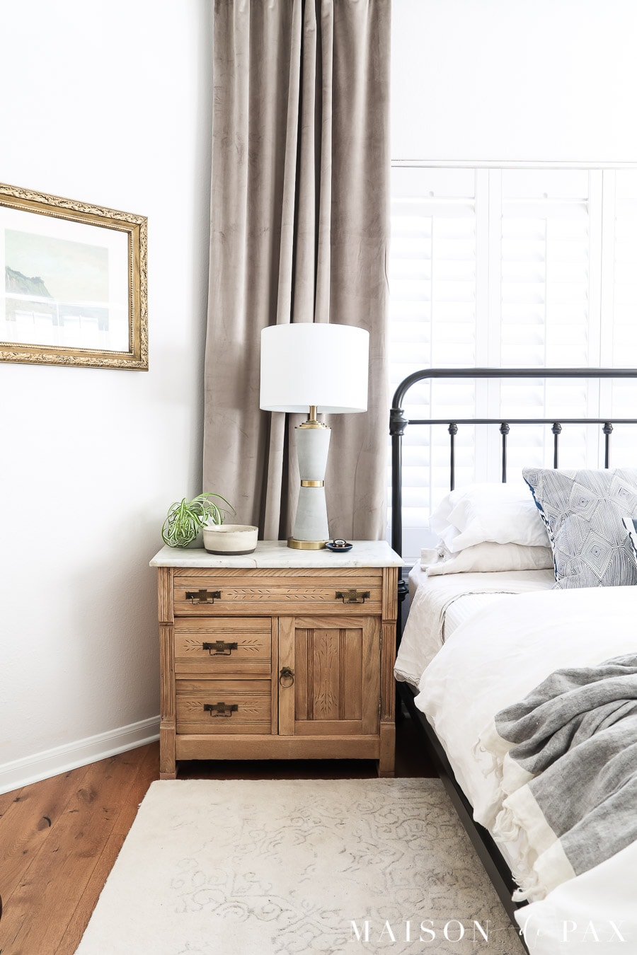 metal bed in front of window with antique nightstand