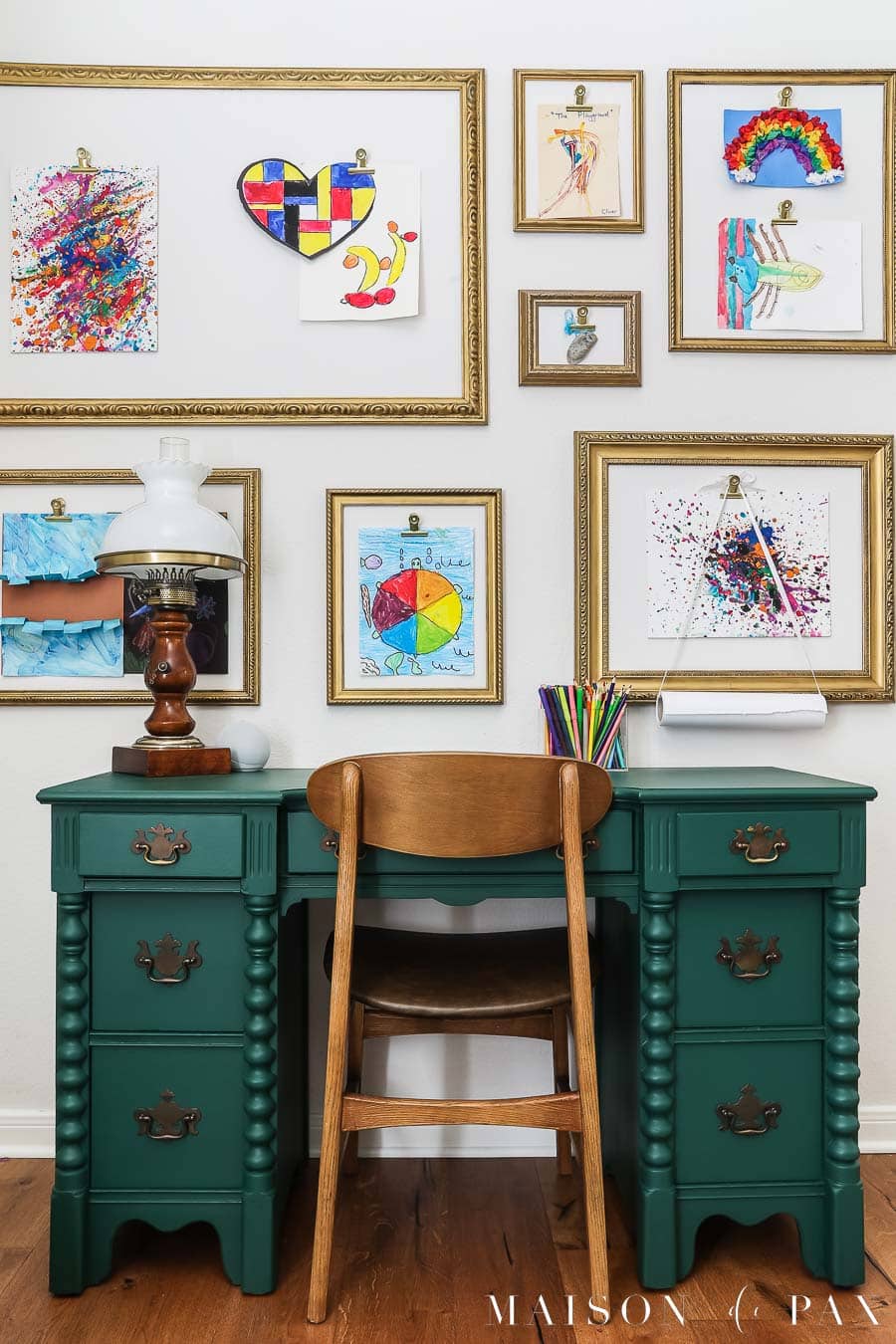 antique desk painted green with vintage wood chair and colorful artwork above