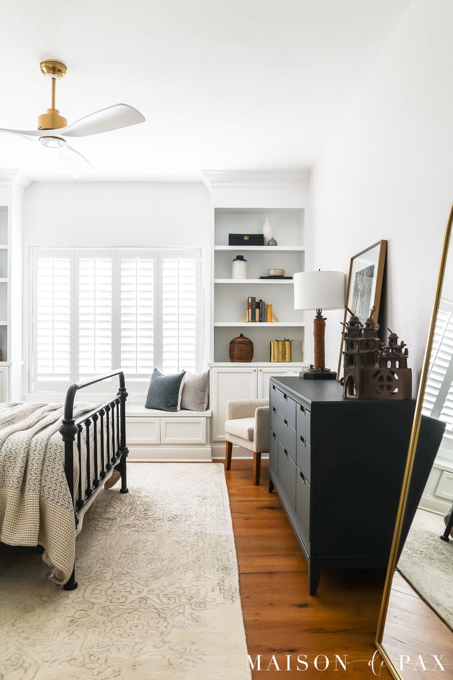 white bedroom with built-in bookcases and window bench