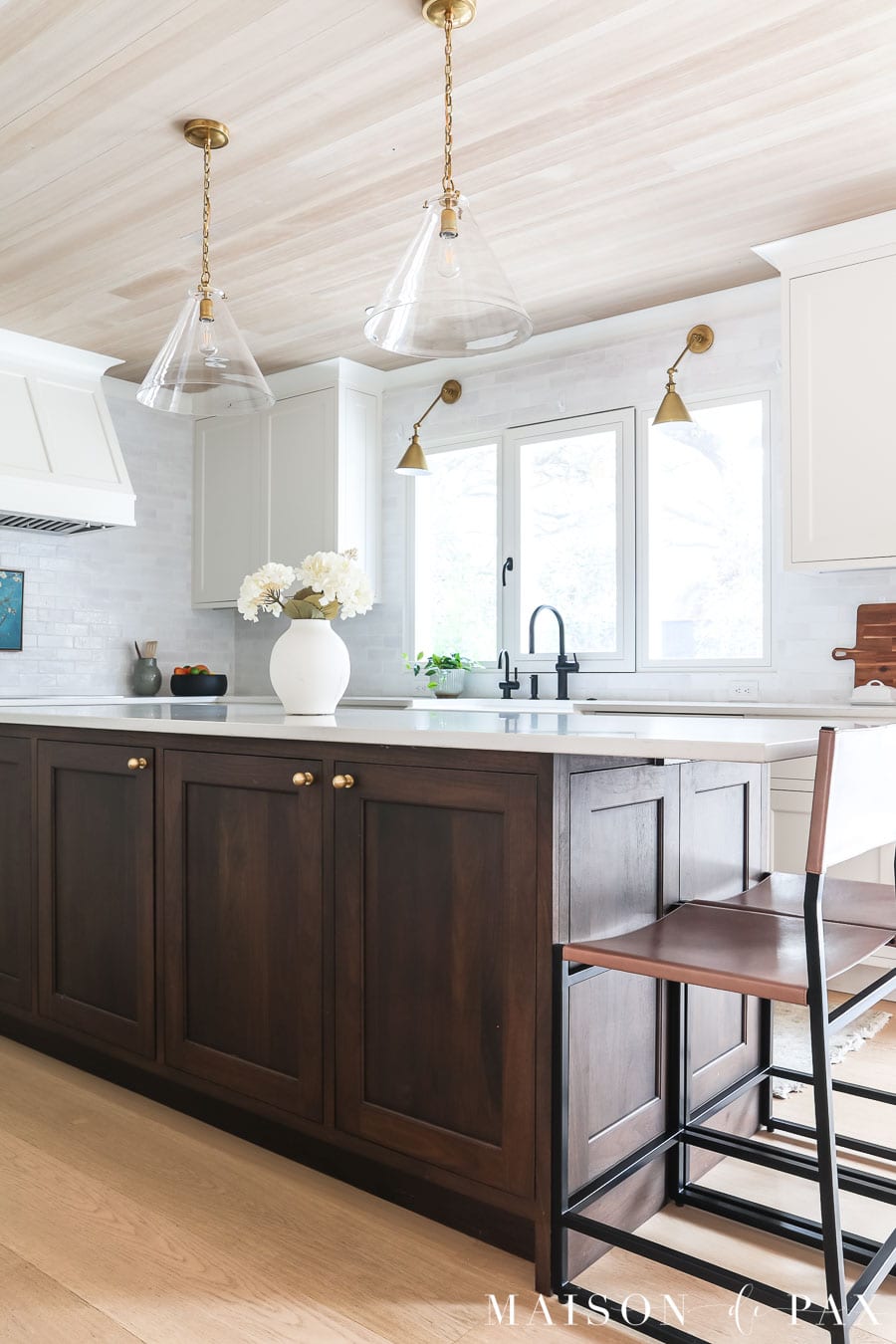 dark wood island with counter stools in white kitchen
