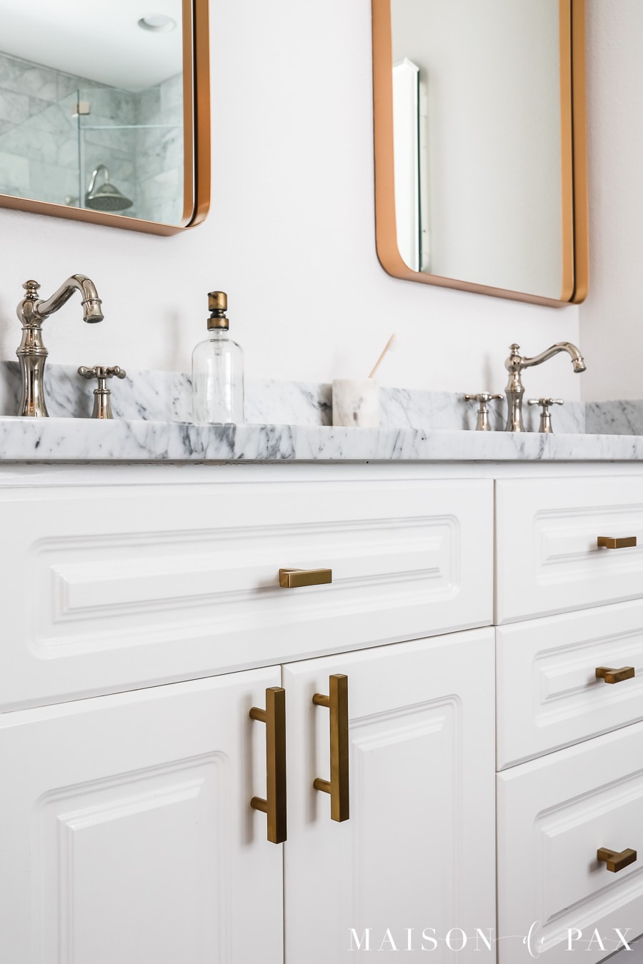 white bathroom cabinets with brass cabinet hardware and marble countertops