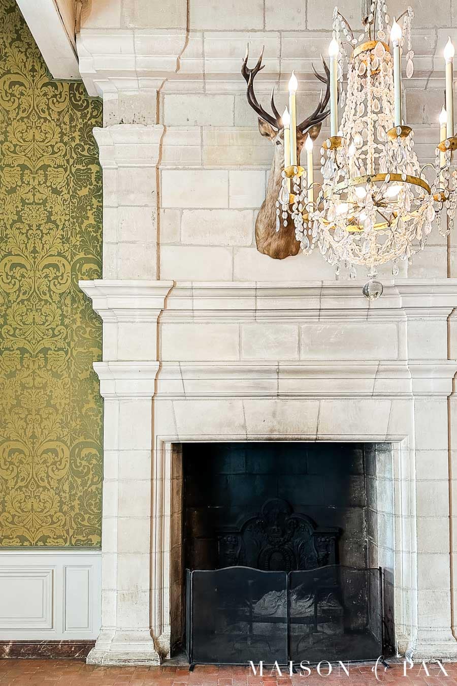 large stone fireplace and crystal chandelier at Chateau de Chambord