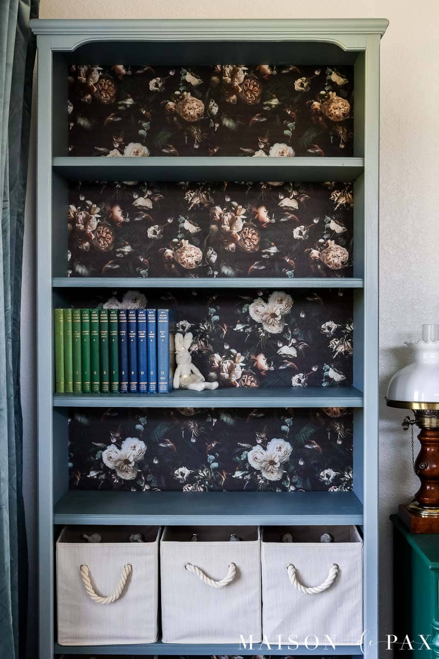 pretty gray blue bookcase with fun floral wallpaper backing