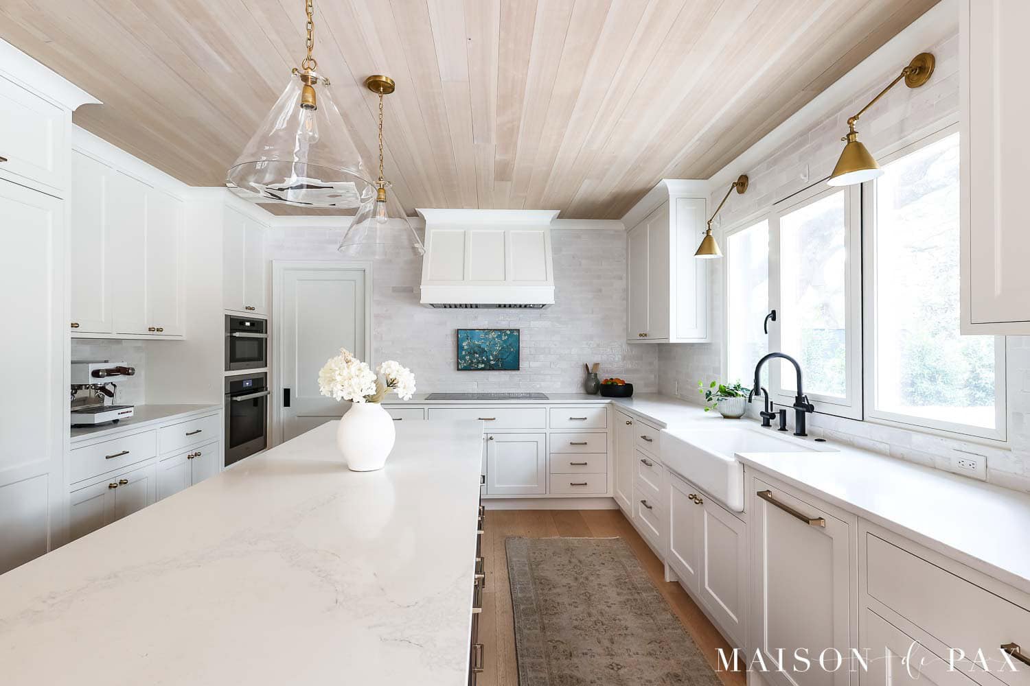Sherwin Williams Pure White kitchen cabinets with white oak ceiling and brass lighting