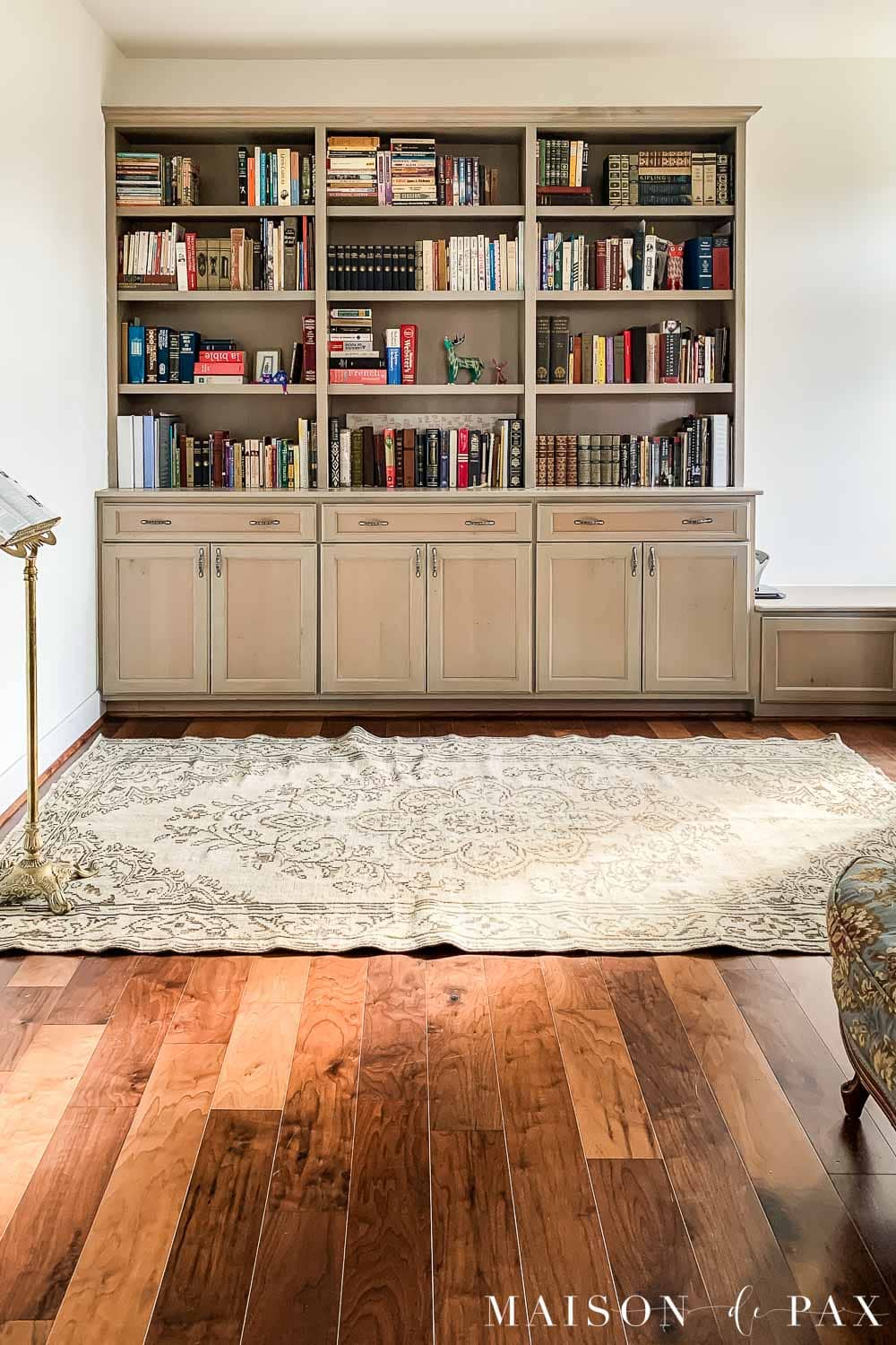 South-facing room with Sherwin Williams Alabaster walls, warm wood floors, and taupe built-in bookshelves in natural light