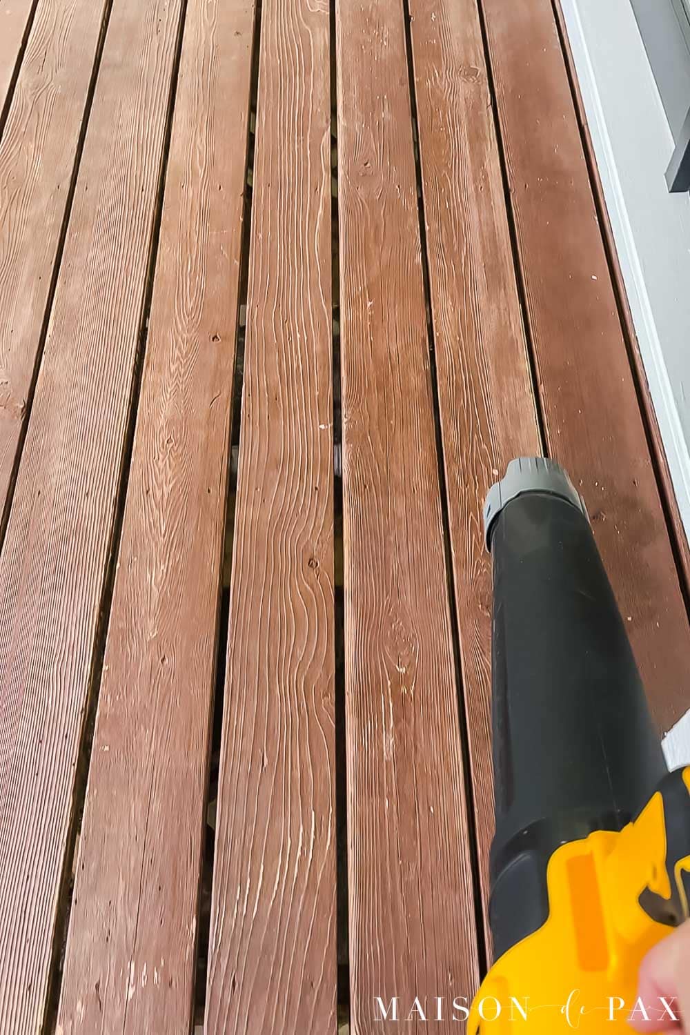 Blowing sanding dust off a porch before restaining it