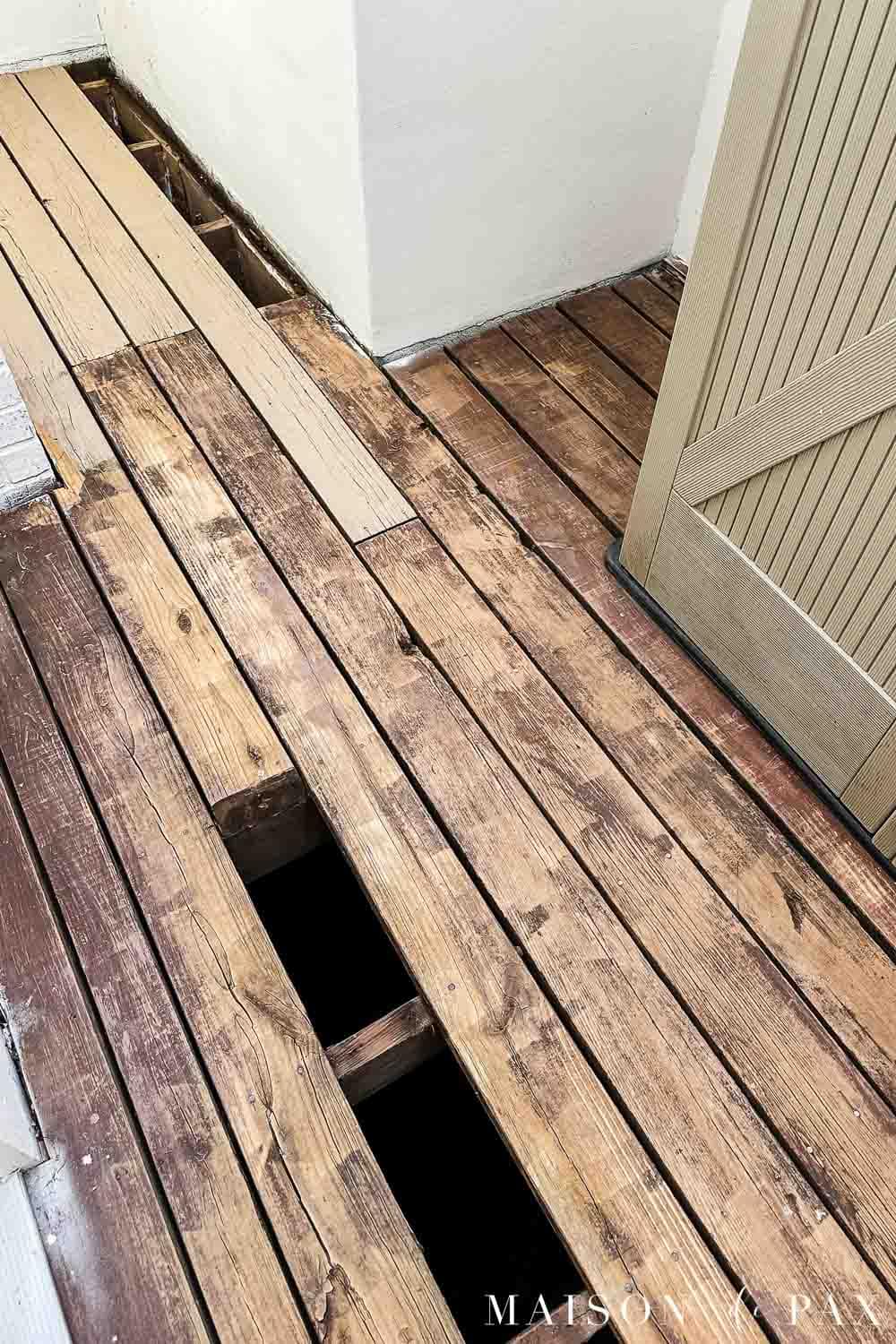 Wood porch during repairs with damaged deck boards removed and replacement boards being installed.