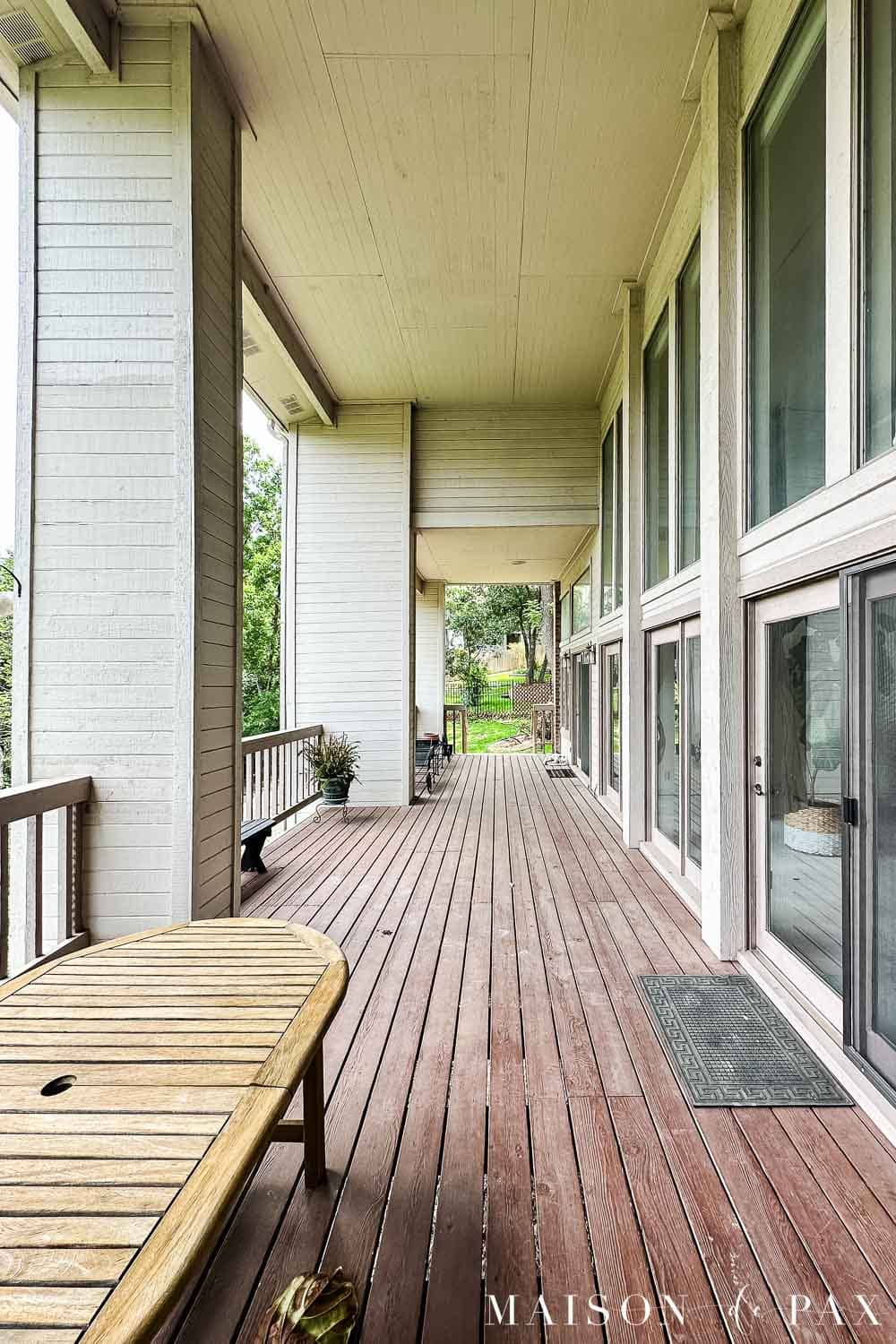 Exterior of a 1980s home before painting, with beigey-mauve siding and trim, red brick, and a reddish-brown stained wood porch.